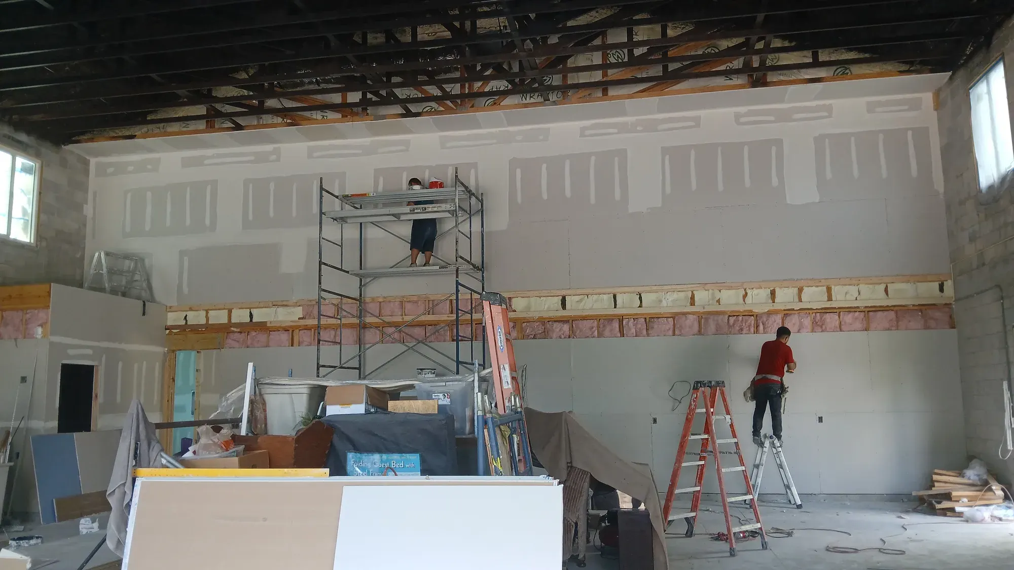 Drywall crew hanging and finishing walls on a tall interior in Lehigh Acres